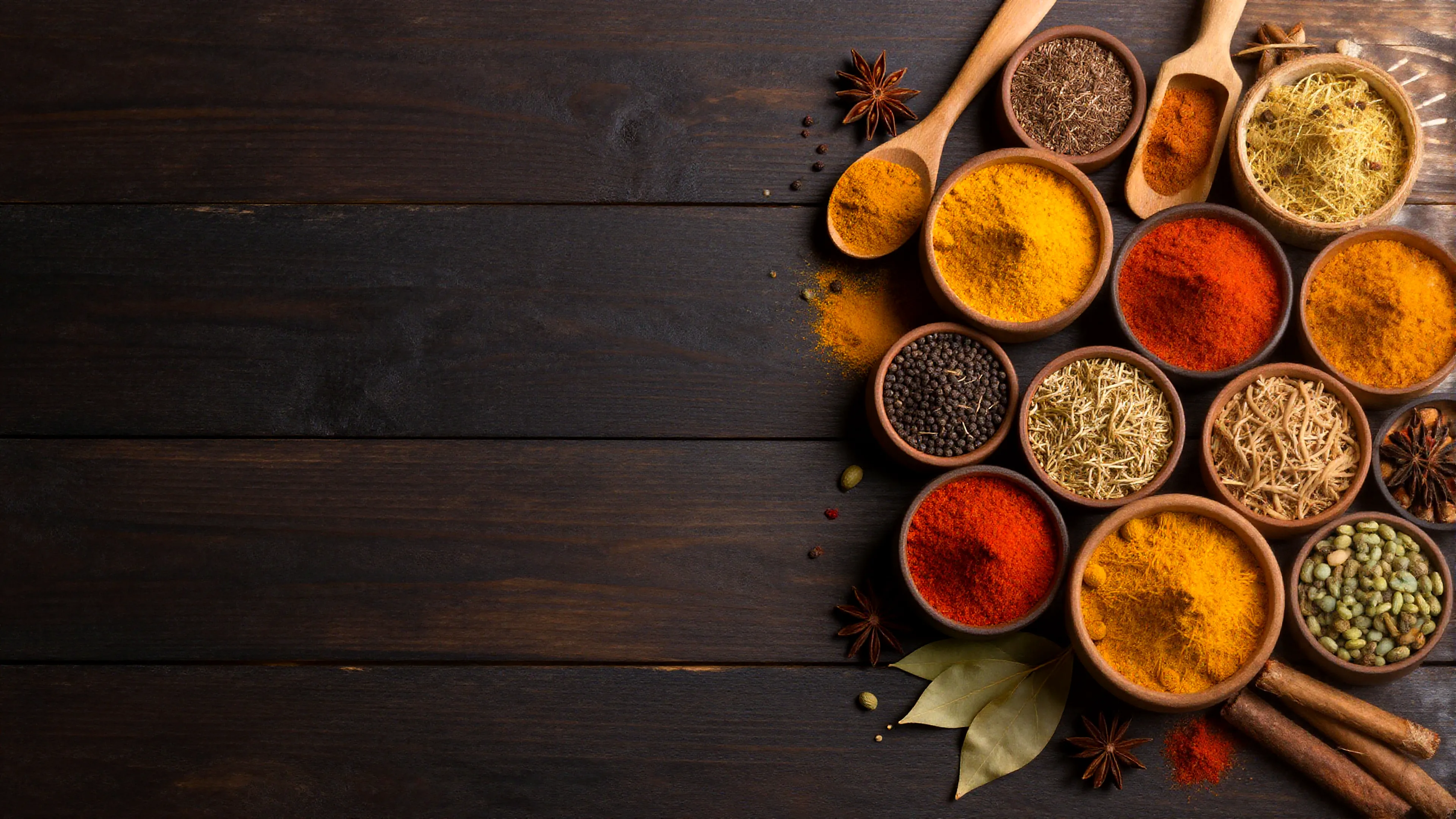 Bowls of colourful Indian spices on a dark wooden table